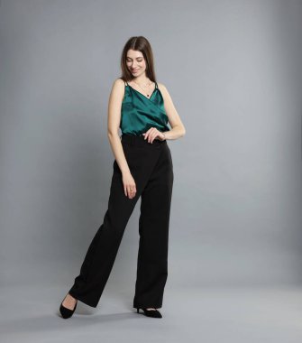 Gri arka planda şık giyinmiş güzel bir kadın.