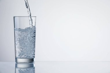 Açık gri arka planda ferahlatıcı soda bardağına dökülüyor, yakın plan. Metin için boşluk