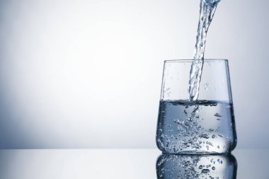 Açık gri arka planda ferahlatıcı soda bardağına dökülüyor, yakın plan. Metin için boşluk