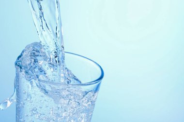 Açık mavi arka planda ferahlatıcı soda bardağına dökülüyor, yakın plan. Metin için boşluk