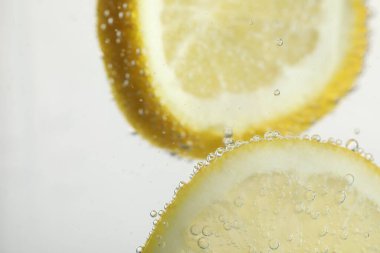 Arka planda limon dilimleri olan soda, yakın plan.