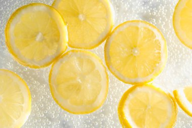 Arka planda limon dilimleri olan soda, yakın plan.