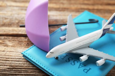 Seyahat sigortası. Uçak modeli, pasaport ve küçük şemsiye ahşap masada, yakın plan.