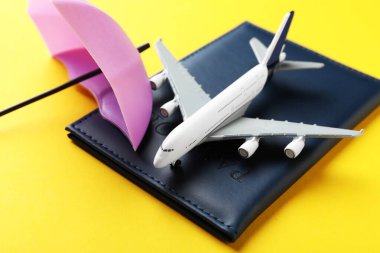 Seyahat sigortası. Uçak modeli, pasaport ve sarı arka planda küçük şemsiye, yakın plan.