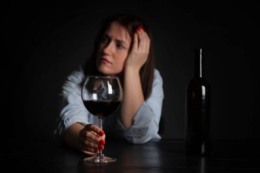 Alkol bağımlılığı. Masasında şarap olan zavallı kadın. Karanlık ve seçici bir odak noktası.