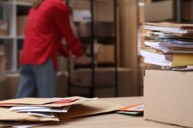 Masada bir sürü farklı zarf ve postanede çalışan kadın, seçici bir odak