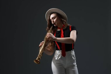 Gri arkaplanda soprano saksafon çalan müzisyen