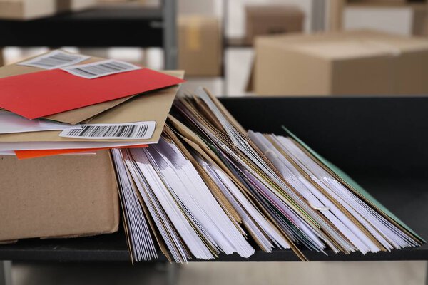Many different envelopes and parcel on shelf in post office