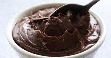 Beyaz masadaki kaşıkla kaseden lezzetli çikolatalı pudingi alıyorum.