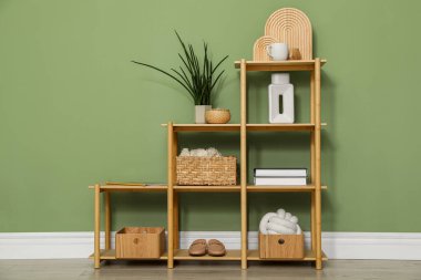 Salon içinde zeytin duvarının yanında farklı dekorasyonu olan ahşap raf ünitesi.