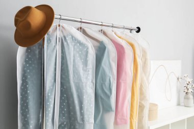 Gri duvarın yanındaki askıda giysi ve şapka var.