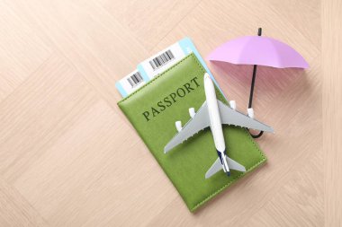 Seyahat sigortası. Uçak modeli, pasaport, küçük şemsiye ve tahta masa üzerindeki biletler. Metin için boşluk