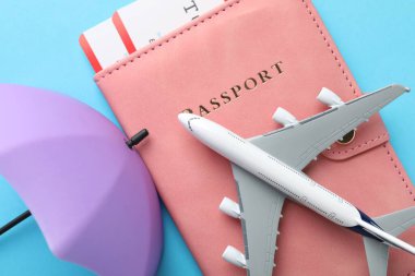 Seyahat sigortası. Uçak modeli, pasaport, küçük şemsiye ve açık mavi arka planda biletler.