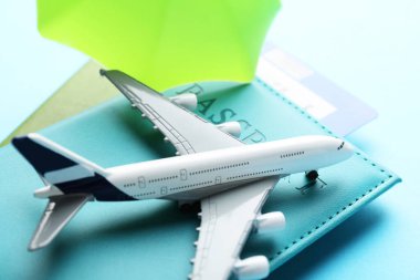 Seyahat sigortası. Uçak modeli, pasaportlar, küçük şemsiye ve açık mavi arka plan bileti, yakın plan.