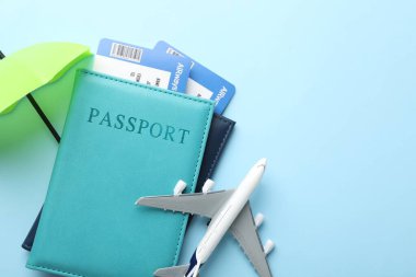 Seyahat sigortası. Uçak modeli, pasaportlar, küçük şemsiyeler ve açık mavi arka planda biletler. Metin için boşluk