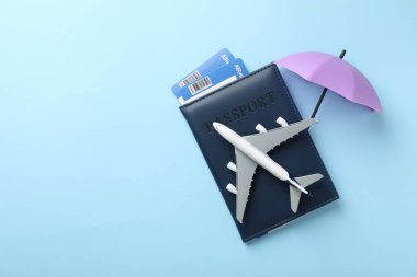 Seyahat sigortası. Uçak modeli, pasaport, küçük şemsiye ve açık mavi arka planda biletler. Metin için boşluk