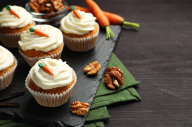 Kremalı havuçlu kekler, cevizler ve siyah ahşap masada taze sebzeler, yakın plan. Metin için boşluk