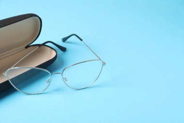 Açık mavi arka planda gözlüklü şık bir çanta, yakın plan. Metin için boşluk