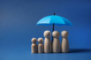 Mavi arka planda şemsiye altında insan figürleri. Sigorta konsepti