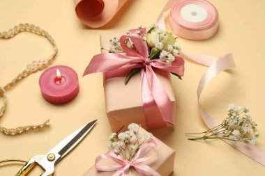 Çiçekçi. Kutular, çiçekler, kurdele, yanan mum ve makas bej arka planda