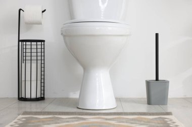 Tuvalet, fırça ve ihtiyaçlar banyoda beyaz duvarın yanında.