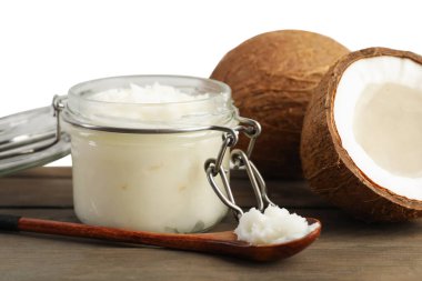 Hindistan cevizleri, pişirme yağı ve kaşık ahşap masada beyaz arka planda