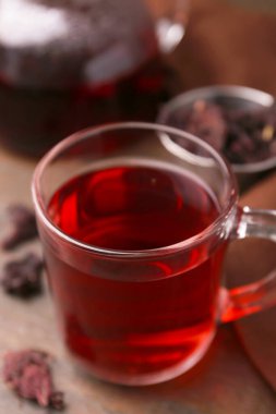 Cam bardakta leziz amber çayı ve ahşap masada kuru roselle sepals, yakın plan.