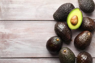 Açık ahşap masada taze olgun avokadolar, düz yerde. Metin için boşluk