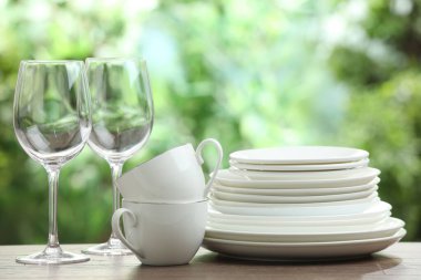 Clean dishware on wooden table against blurred background. Space for text