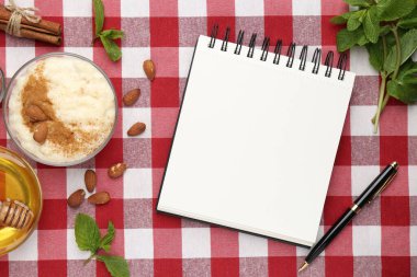 Boş tarif kitabı, tatlı ve malzemeler kırmızı kareli peçete üzerinde, düz uzanmış