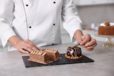 Mutfaktaki masada tatlıları olan profesyonel pasta şefi, yakın plan.