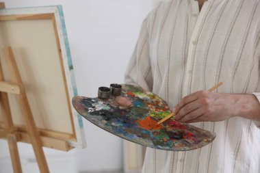 Ressamın stüdyosundaki resim sehpasında boyaları karıştıran adam, yakın plan.