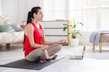 Evde dizüstü bilgisayarı olan bir kadın meditasyon yapıyor. Metin için boşluk