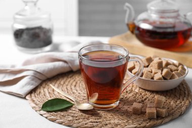 Fincanda koyu siyah çay ve beyaz masada kahverengi şeker küpleri, yakın plan.