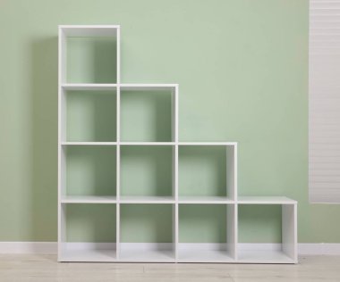 Empty shelving unit near olive wall indoors