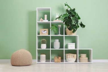 Salonda zeytin duvarının yanında dekorasyonu olan raf ünitesi.