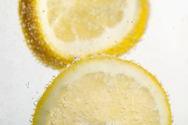 Arka planda limon dilimleri olan soda, yakın plan.