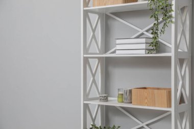 Açık gri duvarın yanındaki raflarda farklı eşyalar var. Metin için boşluk