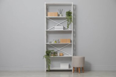 Different items on shelving unit near light grey wall