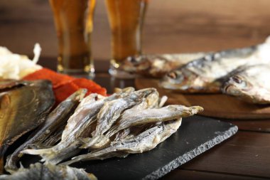 Kurutulmuş balık atıştırmalıkları ve bira ahşap masada, yakın plan.