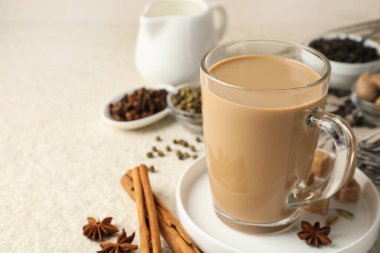 Cam bardakta Aromatik Masala çayı, beyaz desenli masada baharatlar ve esmer şeker, yakın plan. Metin için boşluk