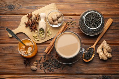 Fincanda Aromatik Masala çayı, baharatlar, kuru yapraklar ve bal ahşap masa üzerinde, düz yatıyordu.