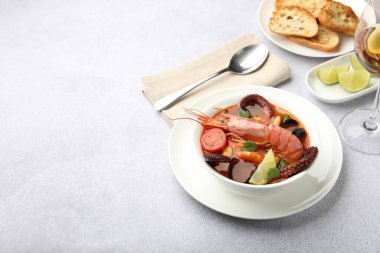 Açık gri masada servis edilen lezzetli deniz ürünleri çorbası, metin için yer.