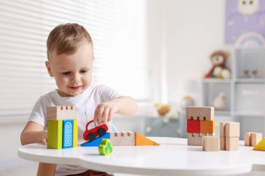 Motor beceri geliştirme. Küçük çocuk beyaz masada oyuncaklarla oynuyor.