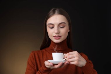 Kahverengi arka planda kahve fincanı olan bir kadın.