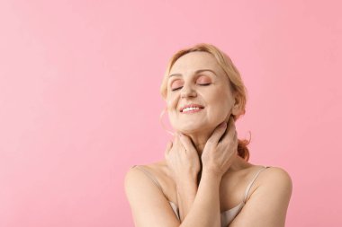 Pembe arka planda gülümseyen orta yaşlı kadın. Metin için boşluk