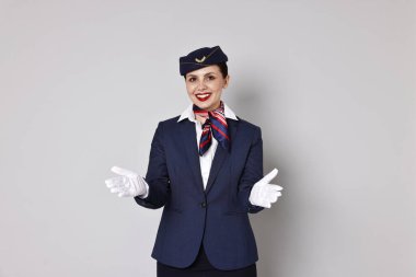 Gülümseyen uçuş görevlisi gri arka planda güvenlik talimatı veriyor