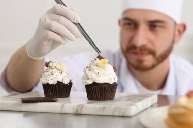 Şekerci, lezzetli kekler yapıyor. Mutfaktaki masada çikolata traşlı. Seçici bir odak noktası.