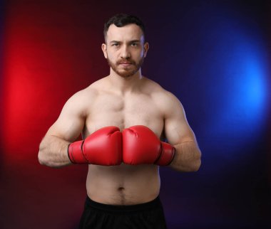 Siyah arka planda, neon ışıklarda boks eldivenli adam.