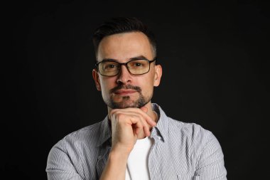 Siyah arka planda orta yaşlı yakışıklı bir adamın portresi.